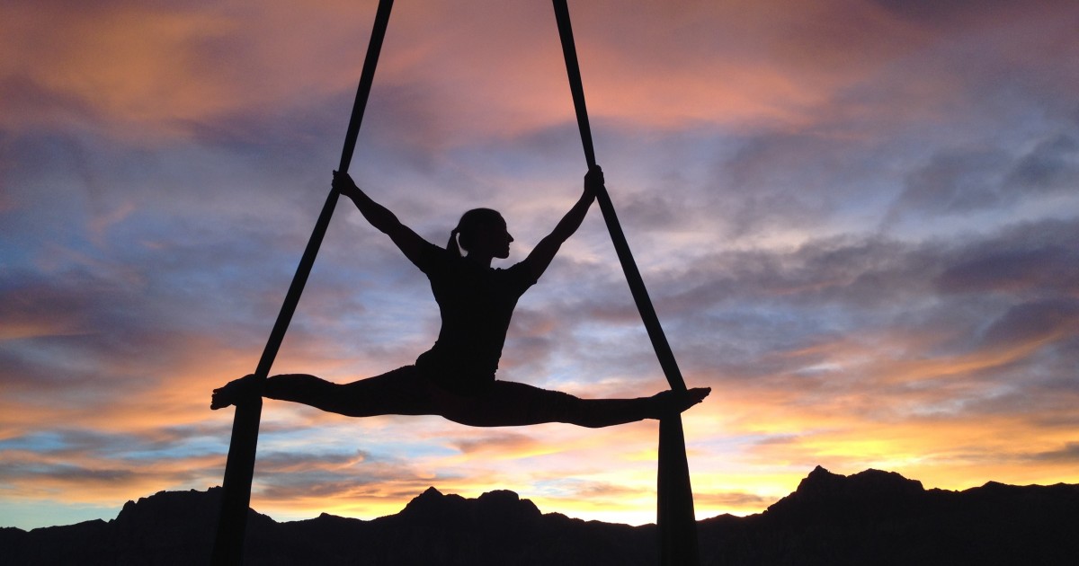 Aerial dancer hanging from ribbons while doing the splits