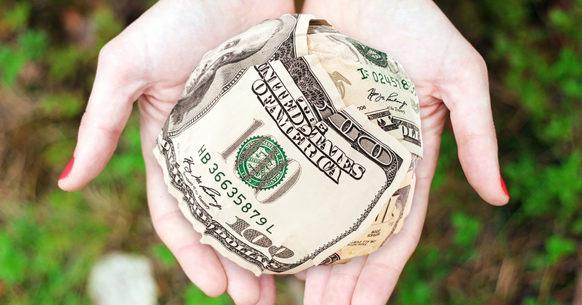 A beautifully spherical ball of money held in a woman's hands